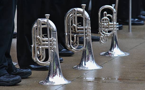 a trio of trumpets set to wet pavement during a parade break.